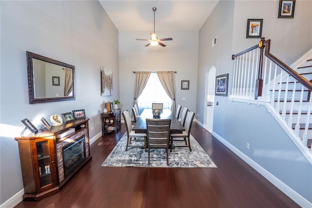 dining room featuring arched walkways, wood finished floors, stairs, and baseboards