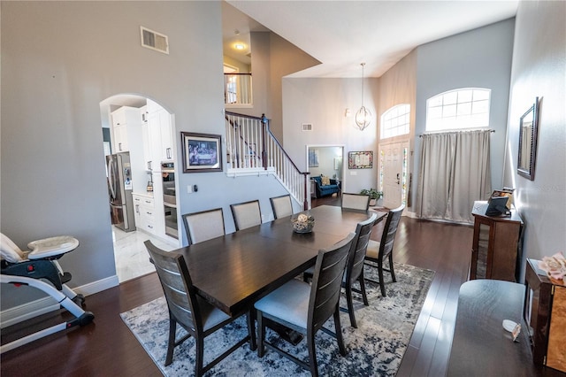 dining space with a high ceiling, stairway, wood finished floors, and visible vents