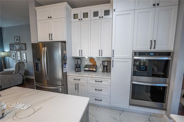 kitchen with stainless steel appliances, marble finish floor, white cabinetry, and open floor plan