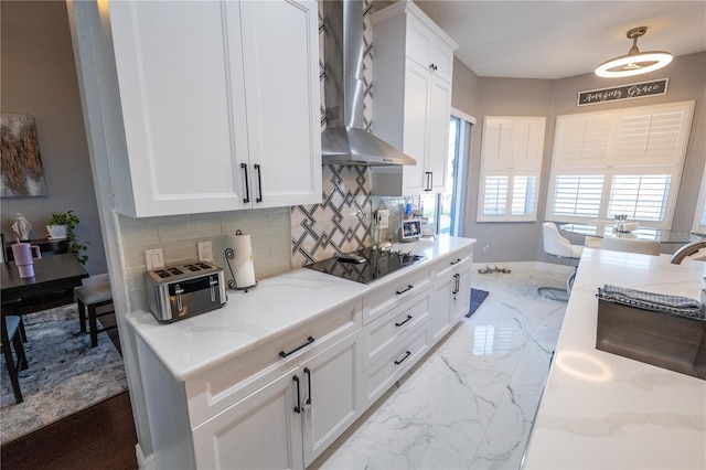 kitchen with black electric stovetop, light stone counters, white cabinets, marble finish floor, and wall chimney range hood