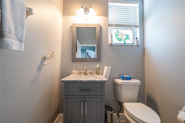 bathroom featuring vanity, toilet, and baseboards