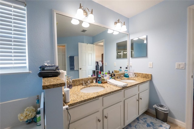 full bathroom with double vanity, a sink, visible vents, and baseboards