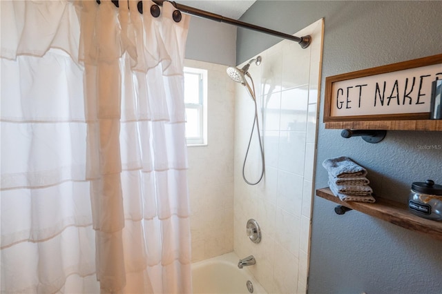 bathroom with a textured wall and shower / tub combo