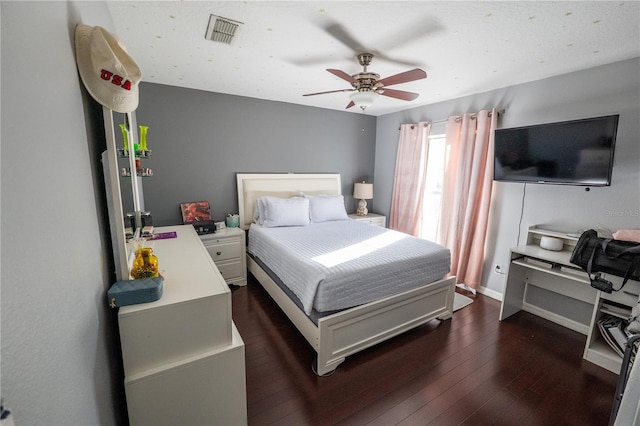 bedroom featuring dark wood-style floors, visible vents, baseboards, and a ceiling fan