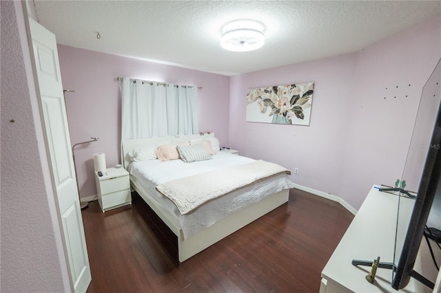 bedroom featuring dark wood-style flooring, a textured ceiling, and baseboards