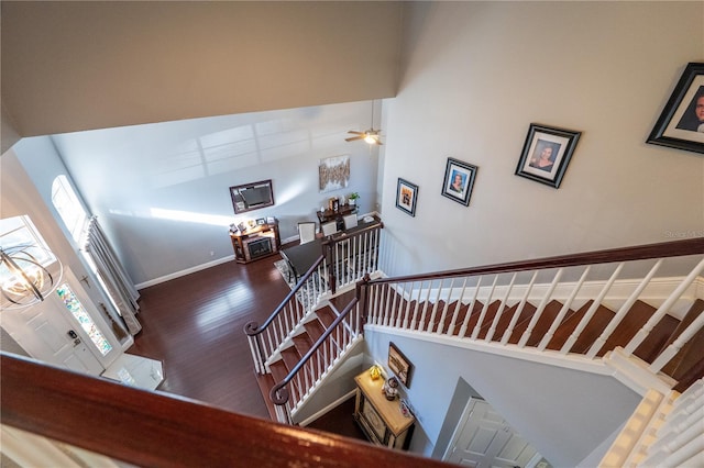 stairs with wood finished floors, a towering ceiling, and baseboards