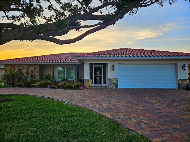 view of front of property featuring a garage, stone siding, driveway, and stucco siding