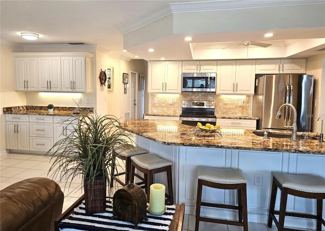 kitchen featuring appliances with stainless steel finishes, ornamental molding, and a breakfast bar area