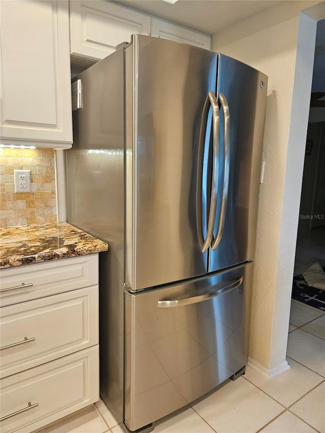 1706 S Lakeside Ct, Venice, FL 34293 - kitchen with light tile patterned flooring, light stone counters, freestanding refrigerator, white cabinetry, and decorative backsplash