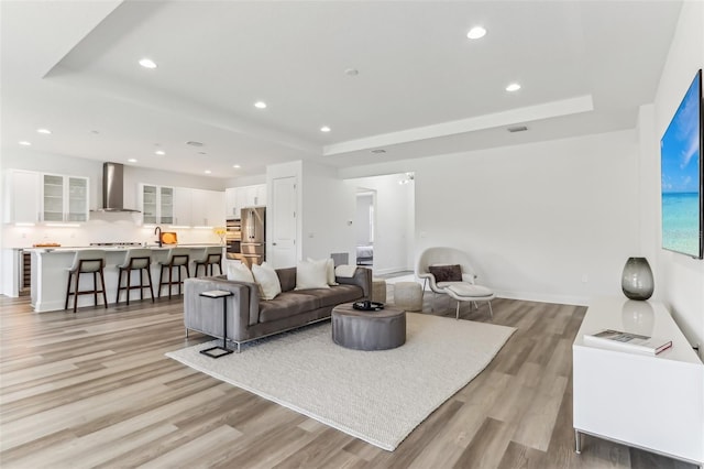 living area featuring light wood-style floors, a raised ceiling, and recessed lighting