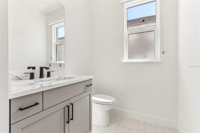 half bath with toilet, plenty of natural light, baseboards, and vanity