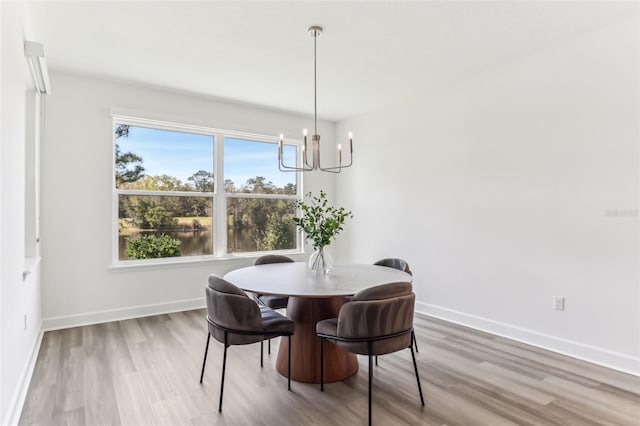 dining space featuring baseboards, a chandelier, and wood finished floors