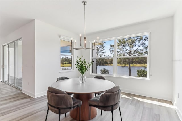 dining room with a notable chandelier, light wood-style flooring, a wealth of natural light, and baseboards