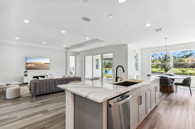 kitchen with visible vents, an island with sink, open floor plan, a sink, and stainless steel dishwasher