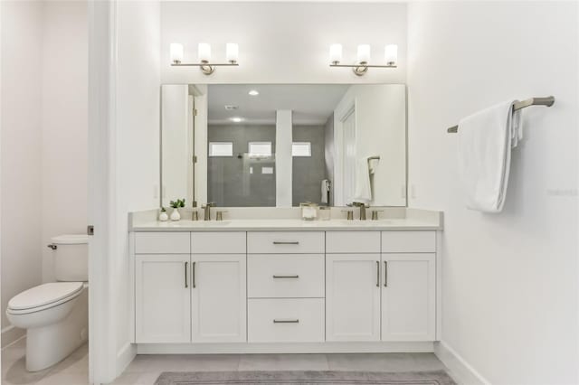 bathroom featuring double vanity, a sink, toilet, and baseboards