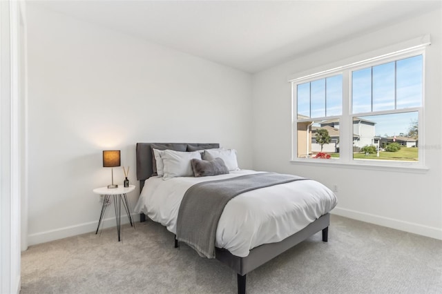 bedroom featuring baseboards and light colored carpet