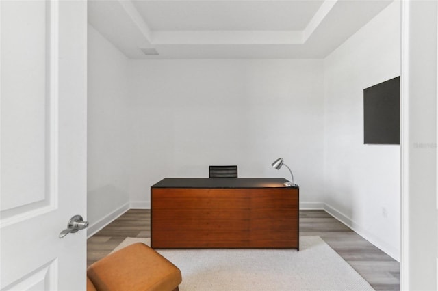 office with baseboards, a raised ceiling, and wood finished floors