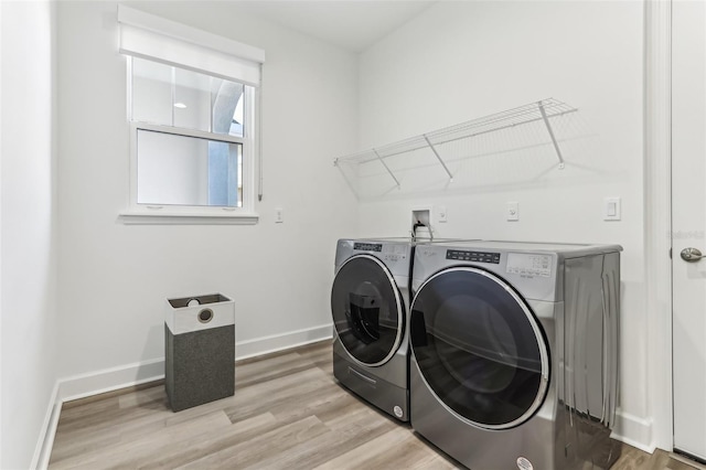 laundry room with laundry area, baseboards, washer and clothes dryer, and light wood finished floors