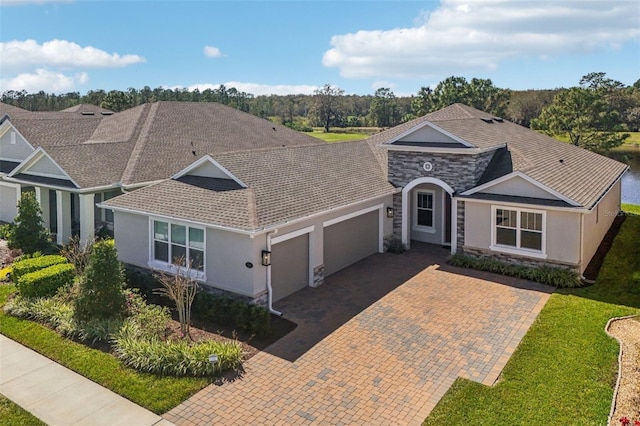 view of front facade featuring decorative driveway, stone siding, an attached garage, and stucco siding