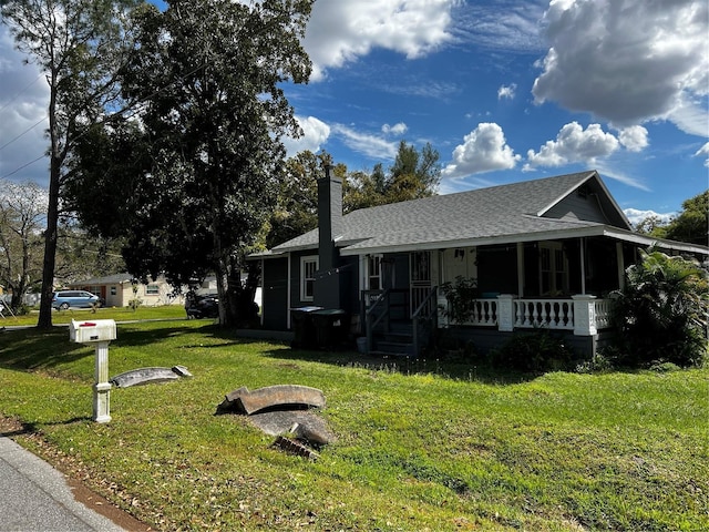 view of front facade with a porch, a shingled roof, a chimney, and a front lawn