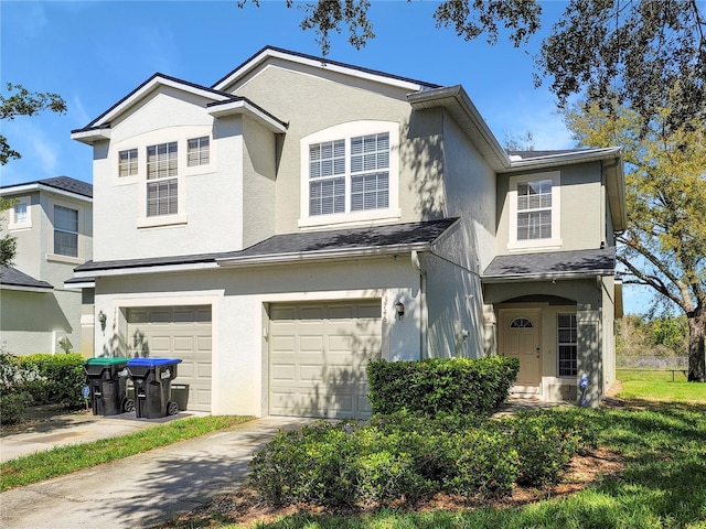 traditional home featuring concrete driveway, an attached garage, and stucco siding