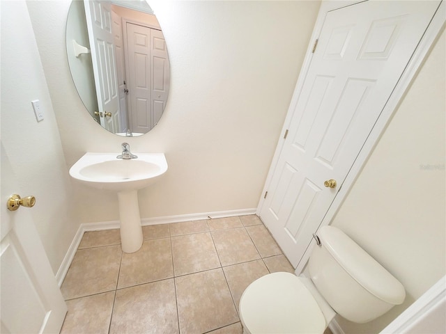 half bathroom featuring toilet, baseboards, and tile patterned floors