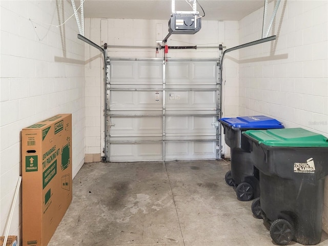 garage featuring concrete block wall and a garage door opener