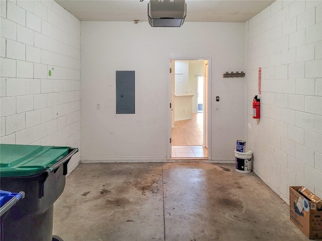 garage featuring a garage door opener, concrete block wall, and electric panel