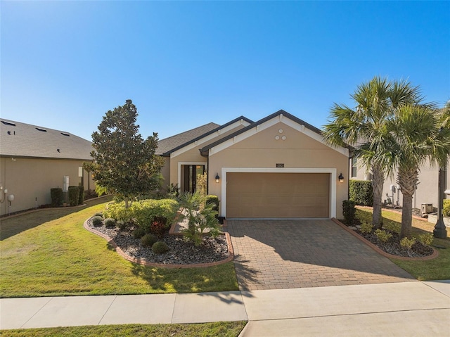 view of front of house with a front lawn, decorative driveway, an attached garage, and stucco siding