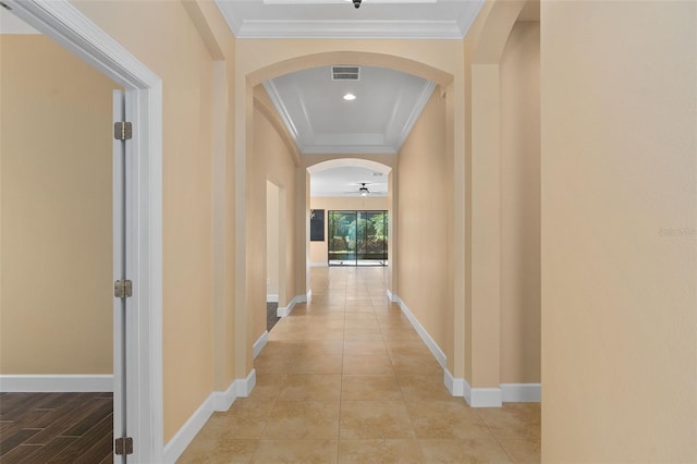 corridor featuring arched walkways, crown molding, light tile patterned floors, visible vents, and baseboards