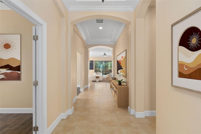 hall with light tile patterned floors, baseboards, visible vents, arched walkways, and crown molding