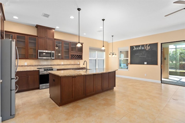 kitchen with stainless steel appliances, a sink, a ceiling fan, visible vents, and decorative backsplash