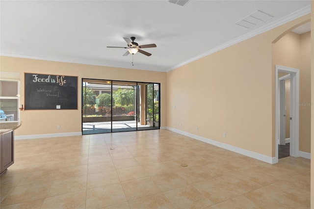 unfurnished room with baseboards, arched walkways, ceiling fan, and crown molding