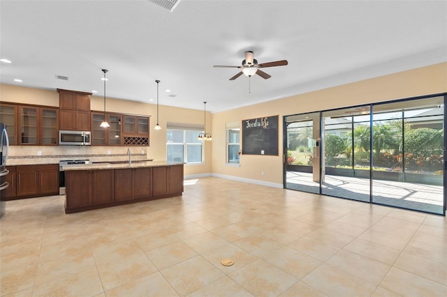 kitchen with ceiling fan, glass insert cabinets, appliances with stainless steel finishes, open floor plan, and backsplash