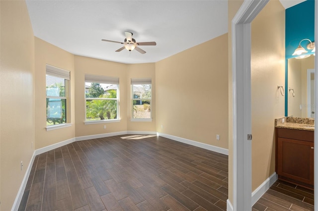 empty room featuring baseboards, ceiling fan, and wood tiled floor