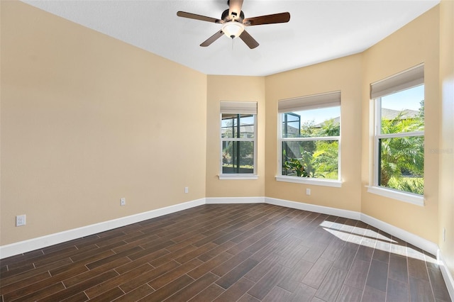 empty room featuring dark wood-type flooring, a ceiling fan, a wealth of natural light, and baseboards