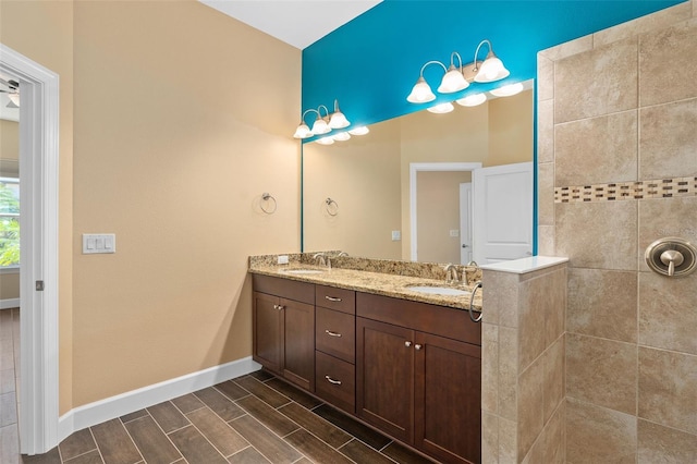 full bathroom with wood tiled floor, a sink, baseboards, and double vanity