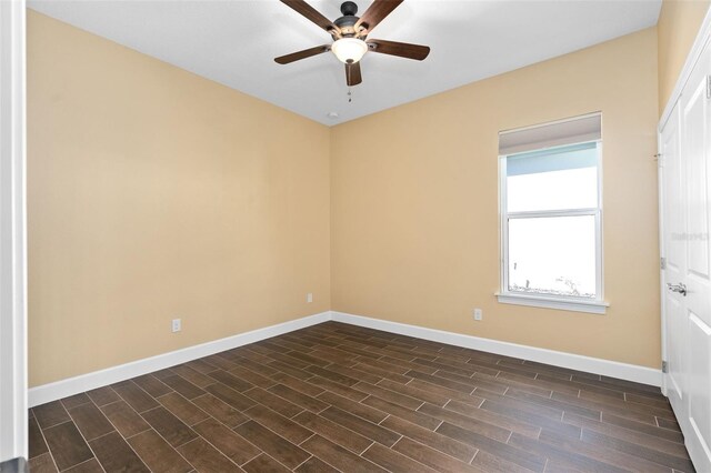 spare room featuring dark wood-style floors, ceiling fan, and baseboards