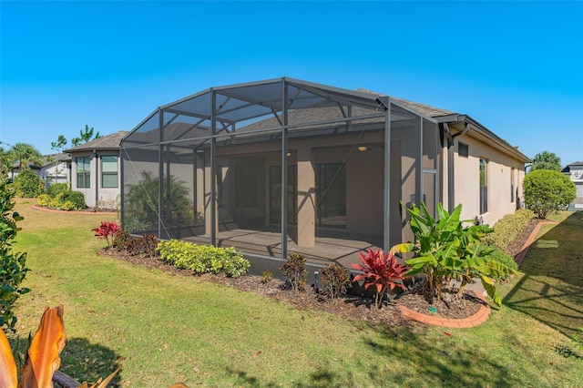 back of house featuring a yard, a lanai, and stucco siding