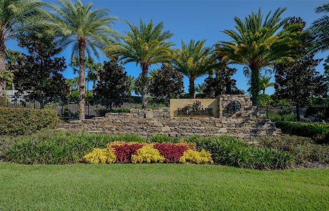 community / neighborhood sign featuring fence and a yard