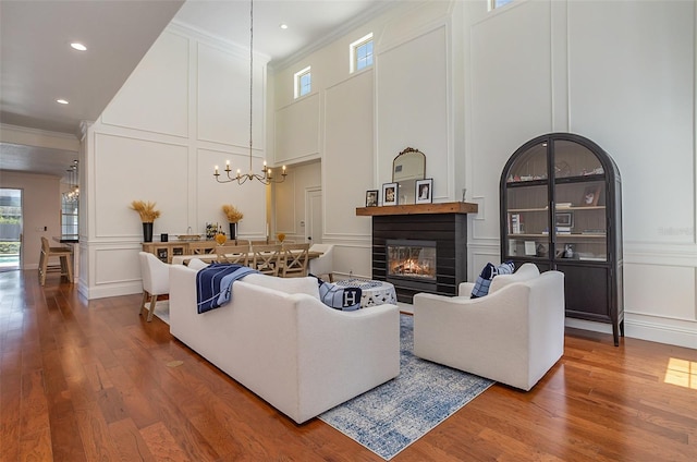 living area with a notable chandelier, crown molding, a glass covered fireplace, and a decorative wall