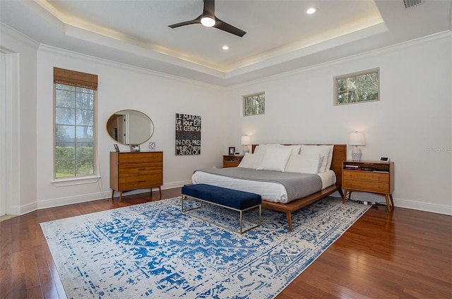 bedroom with a tray ceiling, wood-type flooring, and baseboards