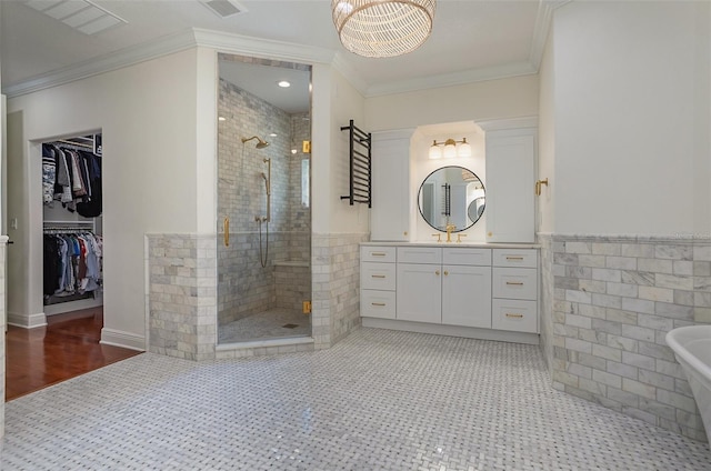 bathroom featuring a stall shower, a walk in closet, crown molding, and tile walls