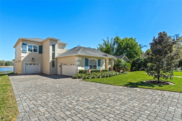 view of front of property featuring stucco siding, decorative driveway, and a front lawn