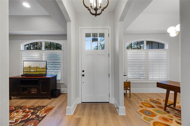 foyer with arched walkways, a healthy amount of sunlight, baseboards, and wood finished floors