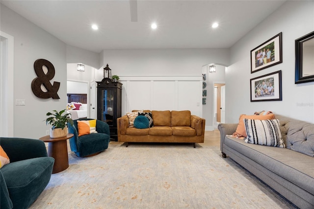 living area featuring arched walkways, a decorative wall, recessed lighting, and light wood-type flooring