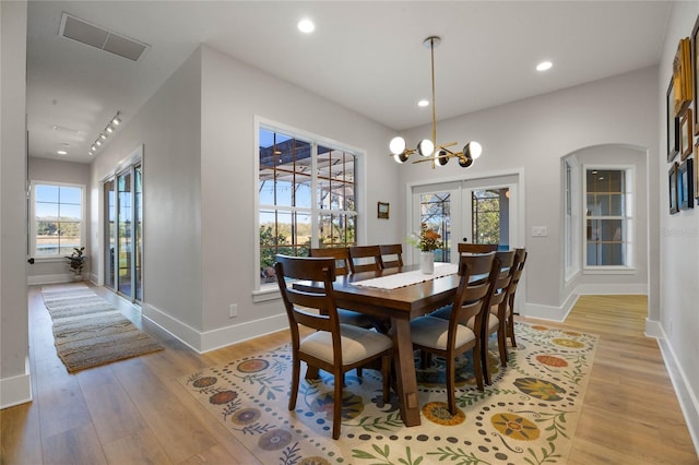 dining space with visible vents, baseboards, light wood-style flooring, recessed lighting, and arched walkways