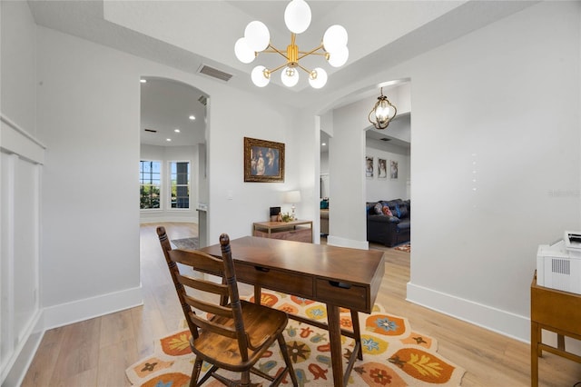 dining room with baseboards, visible vents, arched walkways, and light wood-type flooring