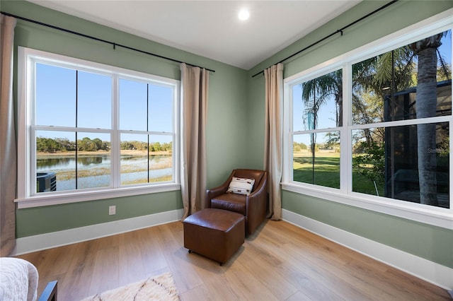 living area with light wood finished floors, baseboards, and a water view