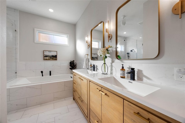 bathroom featuring a garden tub, a stall shower, marble finish floor, and a sink